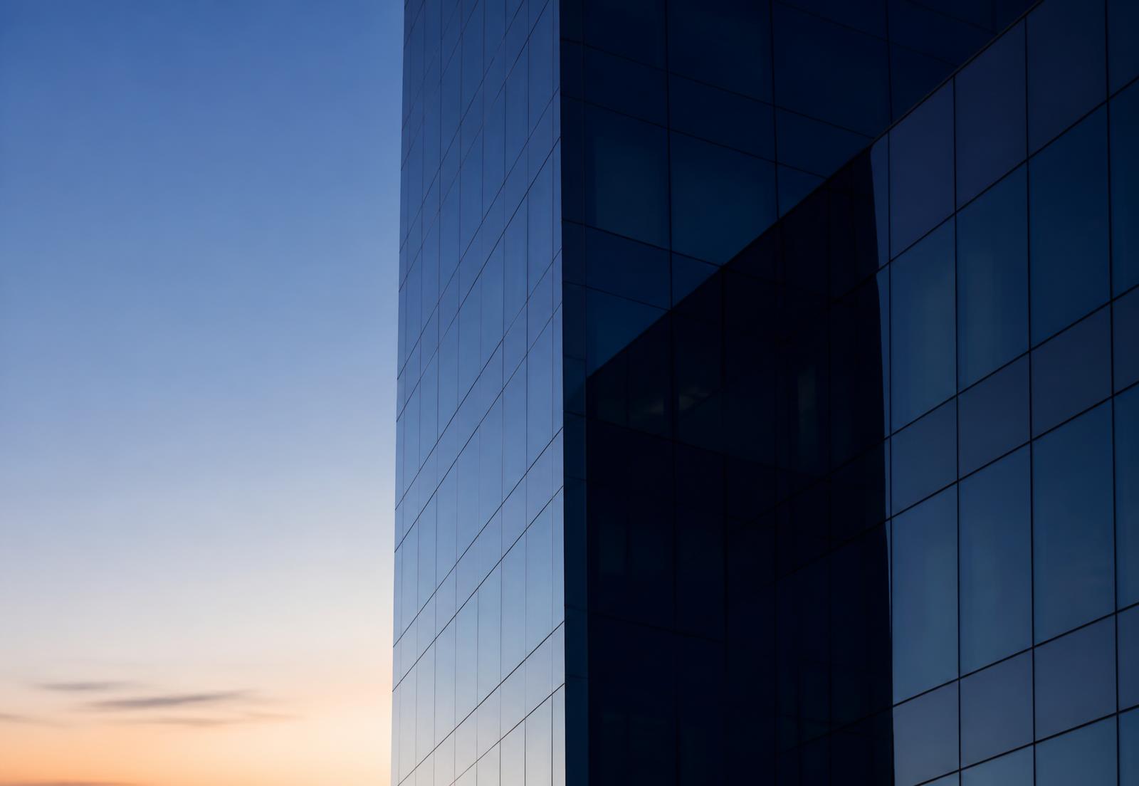 Modern glass office tower at dawn in deep blue light